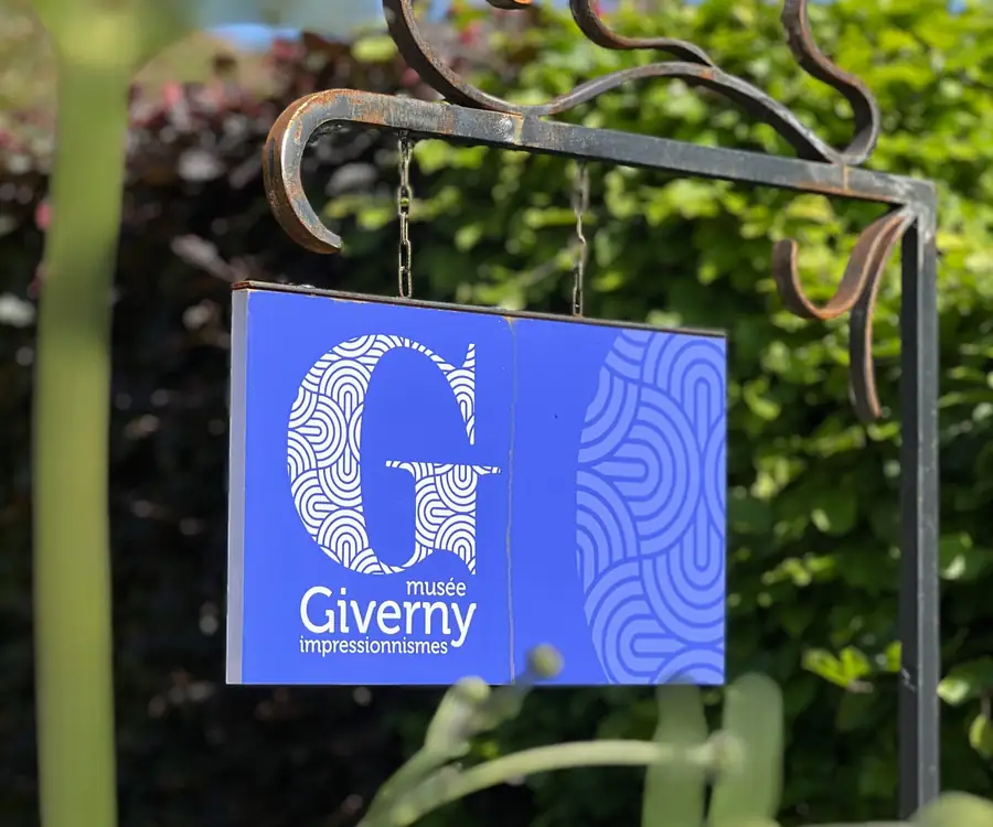 Enseigne du Musée des impressionnismes Giverny dans un jardin fleuri